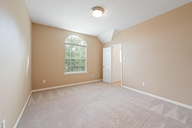 carpeted spare room with a textured ceiling and vaulted ceiling