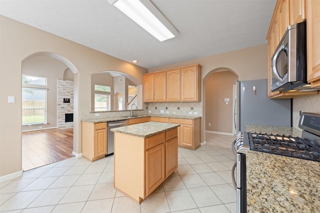 kitchen featuring light brown cabinetry, stainless steel appliances, a kitchen island, and a wealth of natural light