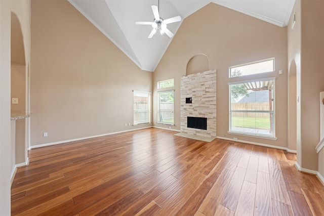 unfurnished living room with a stone fireplace, hardwood / wood-style floors, and high vaulted ceiling