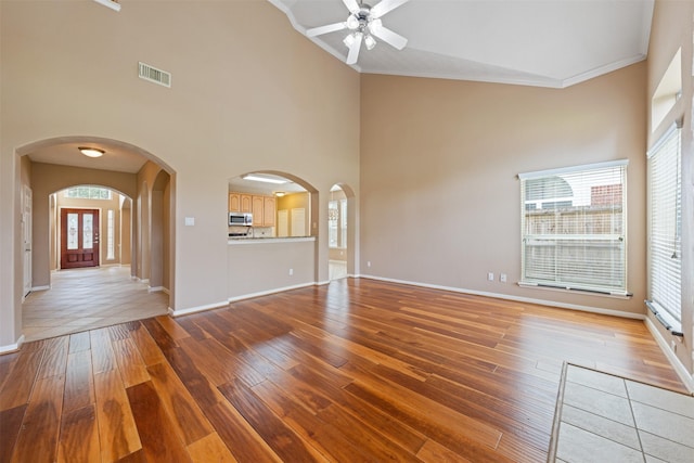 unfurnished living room featuring a wealth of natural light, hardwood / wood-style floors, and crown molding