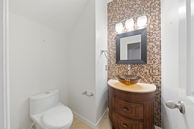 bathroom with vanity, tile patterned floors, vaulted ceiling, decorative backsplash, and toilet