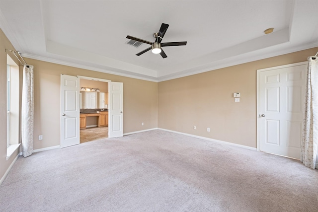 unfurnished bedroom featuring ceiling fan, light colored carpet, and a tray ceiling