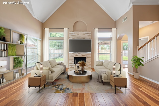 living room with a fireplace, light hardwood / wood-style flooring, high vaulted ceiling, and ornamental molding