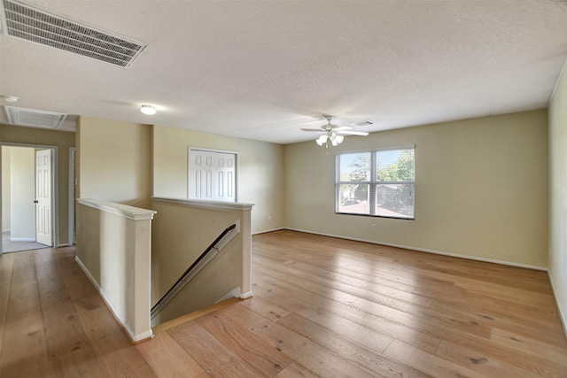 empty room featuring ceiling fan, light hardwood / wood-style floors, and a textured ceiling