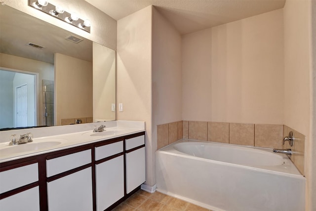 bathroom featuring a tub, tile patterned flooring, vanity, and a textured ceiling