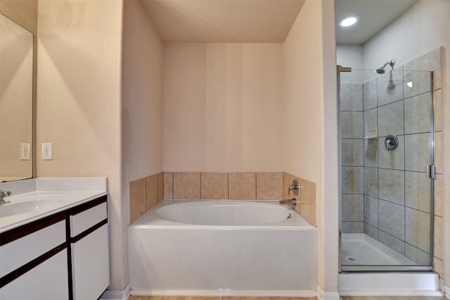 bathroom with a textured ceiling, vanity, and independent shower and bath