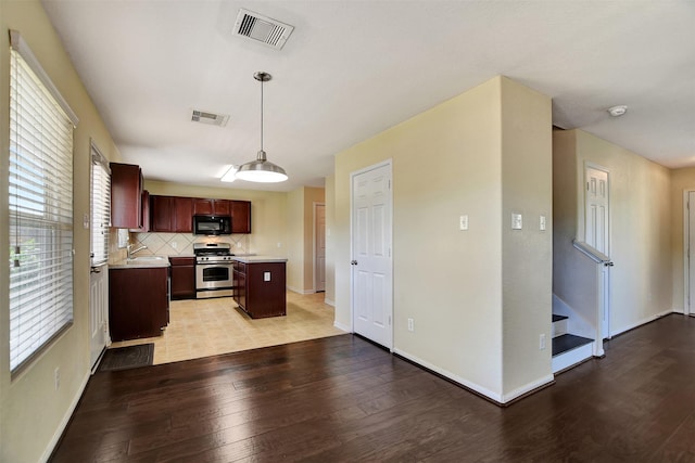 kitchen with tasteful backsplash, gas range, light hardwood / wood-style flooring, and pendant lighting