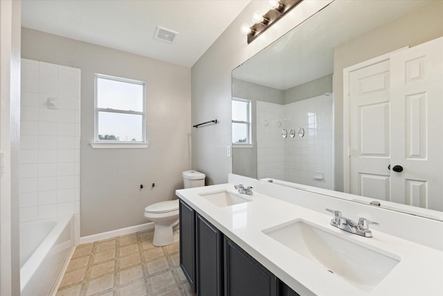 full bathroom with tiled shower / bath, vanity, and toilet