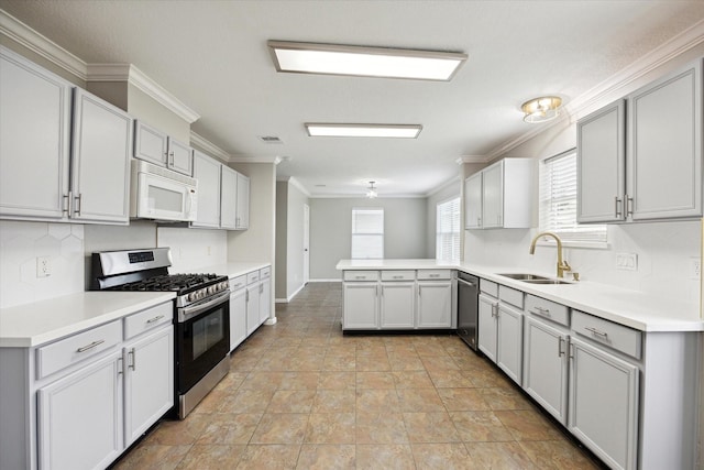 kitchen with sink, ceiling fan, ornamental molding, appliances with stainless steel finishes, and kitchen peninsula