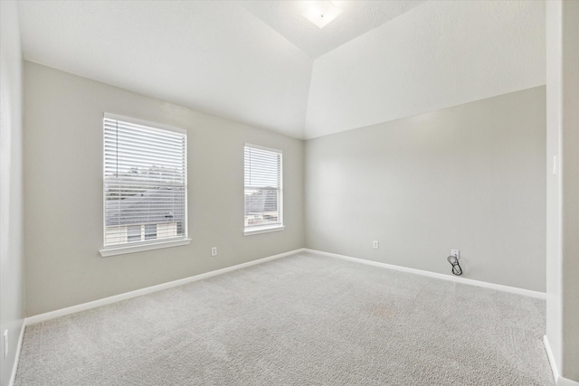 carpeted spare room with lofted ceiling