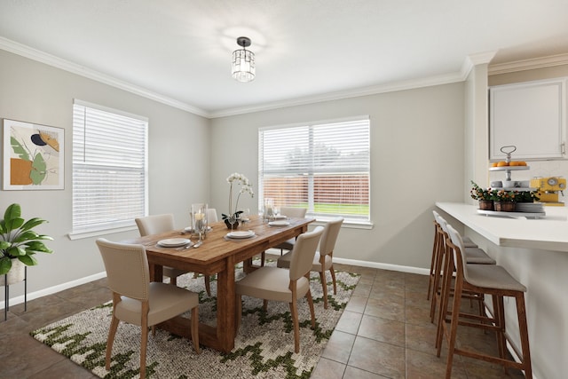 dining space featuring dark tile patterned floors, a healthy amount of sunlight, and ornamental molding