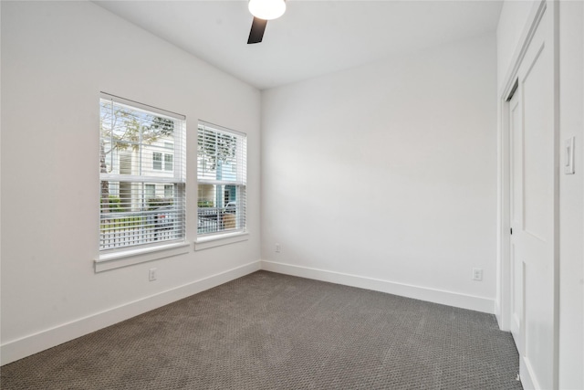 unfurnished room with ceiling fan and dark carpet