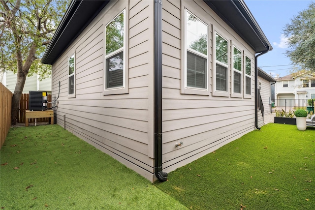 view of side of home with a lawn and central AC