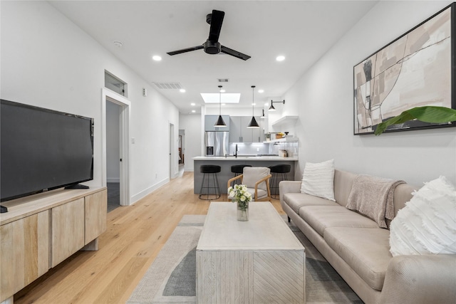 living room featuring light wood-type flooring, ceiling fan, and sink