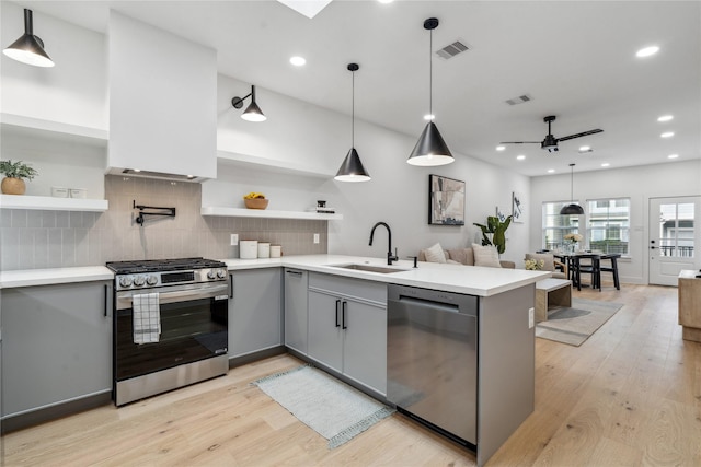 kitchen featuring kitchen peninsula, stainless steel appliances, light hardwood / wood-style flooring, and sink