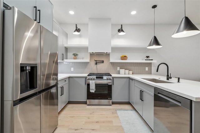 kitchen featuring sink, hanging light fixtures, stainless steel appliances, light wood-type flooring, and custom exhaust hood