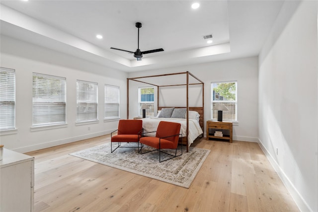 bedroom featuring light wood-type flooring, a tray ceiling, and ceiling fan