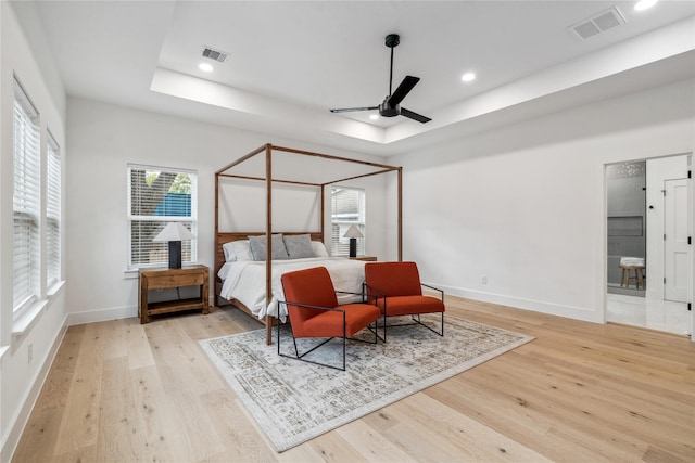 bedroom featuring ceiling fan, a raised ceiling, and light hardwood / wood-style flooring