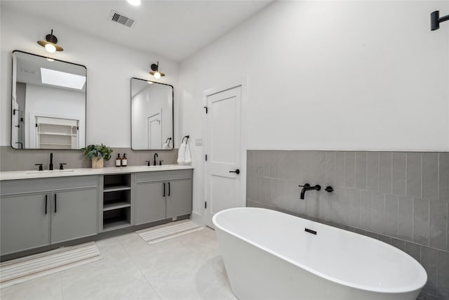 bathroom featuring tile patterned flooring, vanity, a tub to relax in, and tile walls