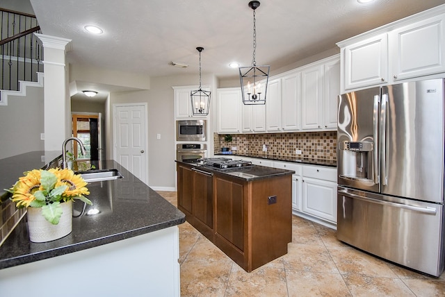 kitchen featuring white cabinetry, sink, hanging light fixtures, stainless steel appliances, and a center island with sink