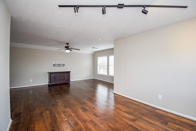 unfurnished living room with a textured ceiling, track lighting, ceiling fan, and dark wood-type flooring