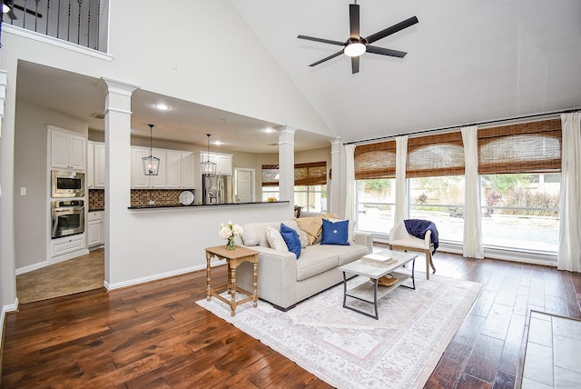 living room with ceiling fan, high vaulted ceiling, a healthy amount of sunlight, and dark hardwood / wood-style floors