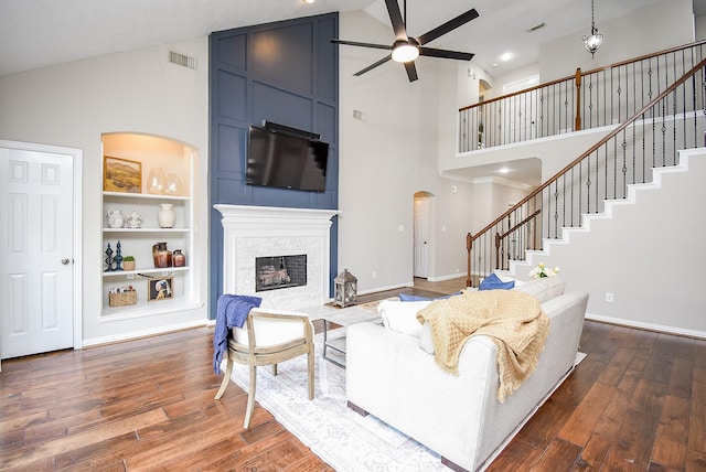 living room with hardwood / wood-style flooring, high vaulted ceiling, ceiling fan, and a stone fireplace