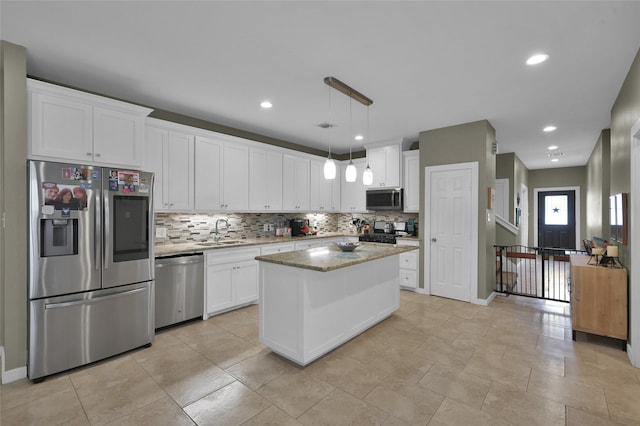 kitchen with stainless steel appliances, sink, pendant lighting, white cabinets, and a kitchen island