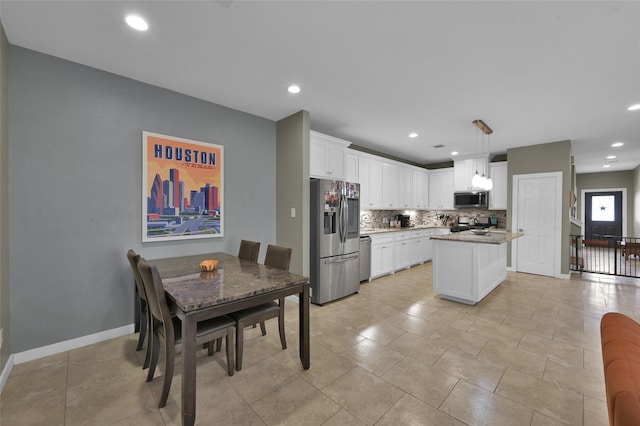 kitchen with appliances with stainless steel finishes, backsplash, decorative light fixtures, white cabinets, and a kitchen island