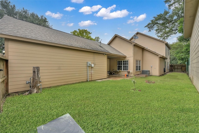 rear view of property with central air condition unit and a yard