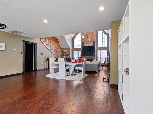 dining room with ceiling fan, dark hardwood / wood-style flooring, a towering ceiling, and a textured ceiling