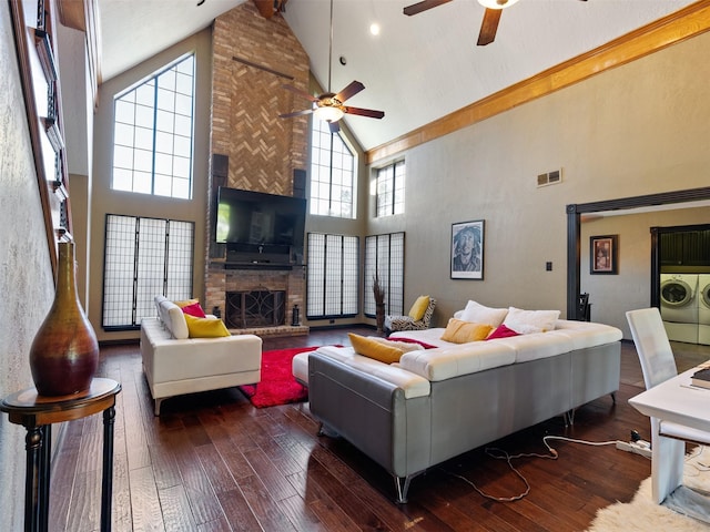 living room with washer and clothes dryer, dark wood-type flooring, high vaulted ceiling, ceiling fan, and a fireplace