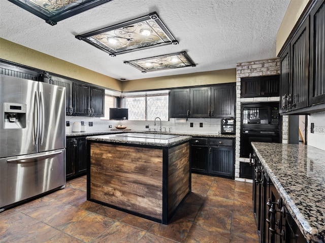 kitchen featuring stone counters, a center island, sink, a textured ceiling, and black appliances