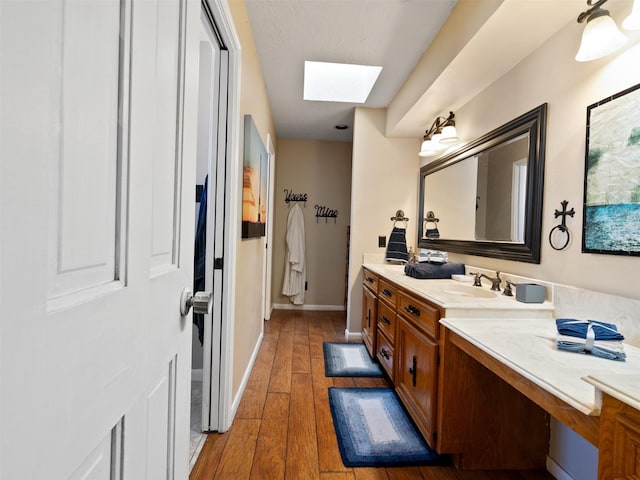 bathroom with wood-type flooring, vanity, and a skylight