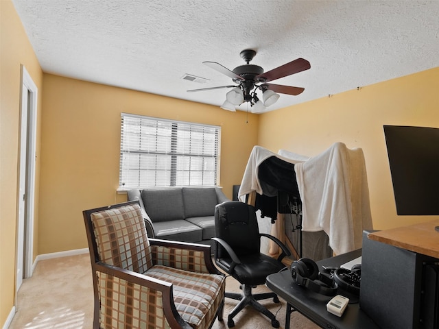 office space featuring a textured ceiling, ceiling fan, and light carpet