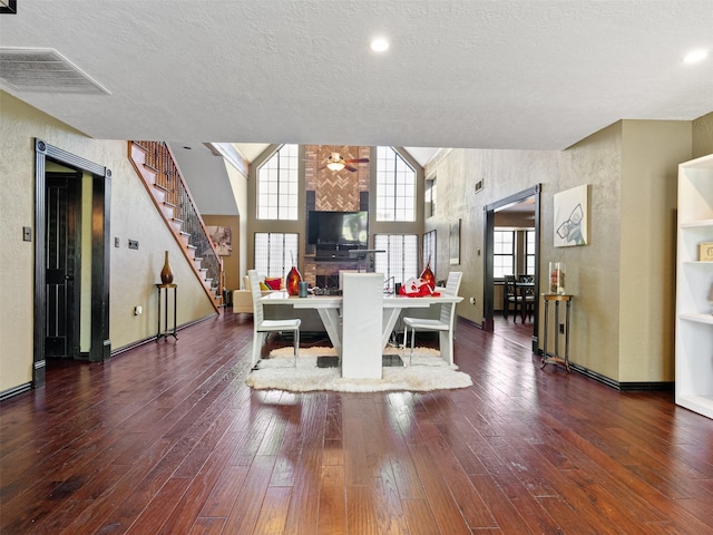 dining area with a wealth of natural light, a high ceiling, dark wood-type flooring, and a textured ceiling