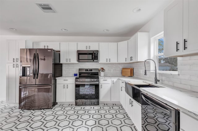 kitchen featuring decorative backsplash, sink, white cabinets, and appliances with stainless steel finishes