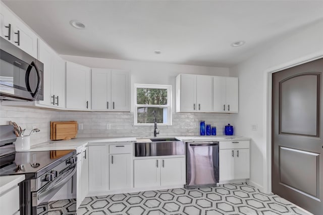 kitchen with stainless steel appliances, white cabinetry, tasteful backsplash, and sink