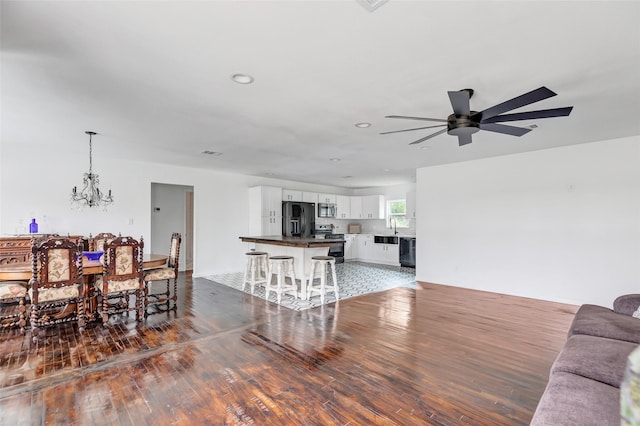 dining area with ceiling fan with notable chandelier, dark hardwood / wood-style flooring, and sink