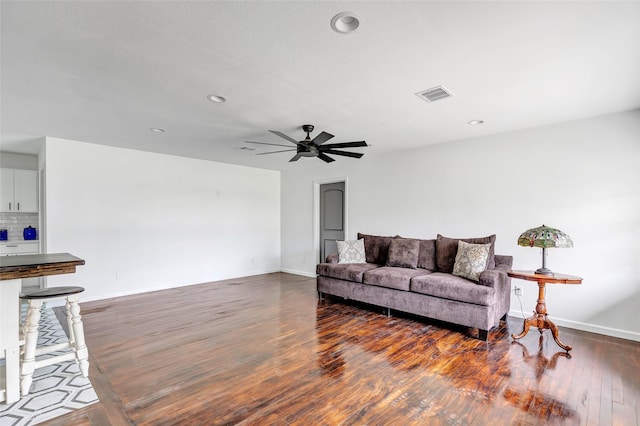 living room featuring ceiling fan and dark wood-type flooring