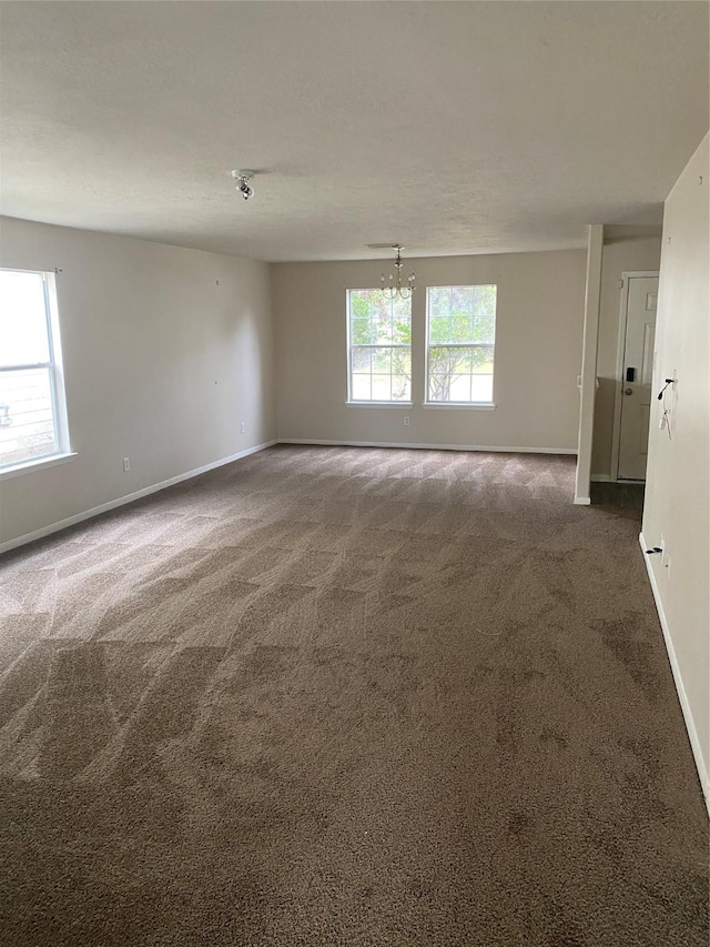 unfurnished room featuring a chandelier and dark carpet