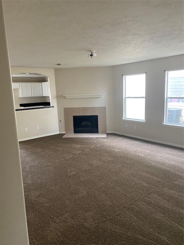 unfurnished living room featuring a textured ceiling, carpet floors, and a fireplace