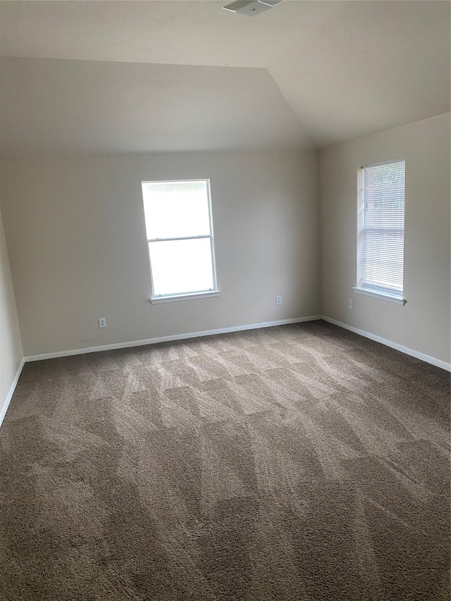 carpeted empty room featuring plenty of natural light and lofted ceiling