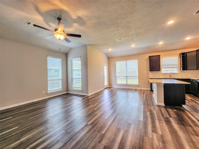 interior space featuring a breakfast bar, a textured ceiling, ceiling fan, dark wood-type flooring, and a kitchen island