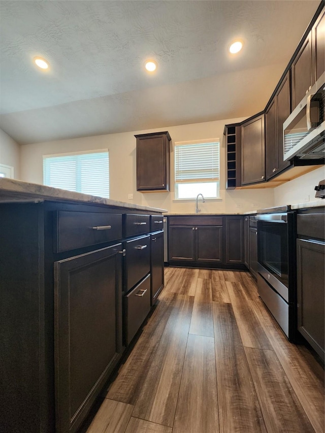 kitchen with dark brown cabinets, stainless steel appliances, hardwood / wood-style flooring, and sink