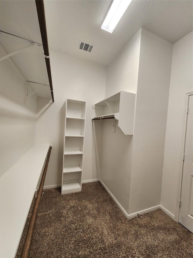 walk in closet with dark colored carpet