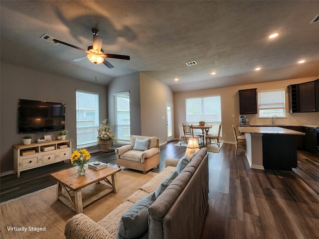 living room featuring ceiling fan, sink, dark wood-type flooring, and a textured ceiling