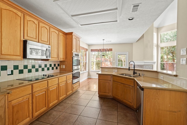 kitchen with backsplash, stainless steel appliances, sink, pendant lighting, and dark tile patterned flooring