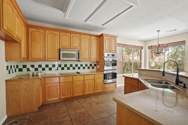 kitchen featuring dark tile patterned flooring, sink, tasteful backsplash, a notable chandelier, and stainless steel appliances