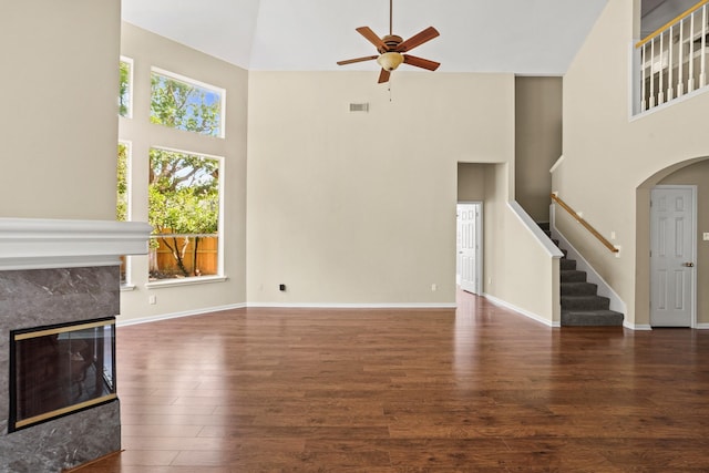 unfurnished living room featuring ceiling fan, dark hardwood / wood-style flooring, and a towering ceiling